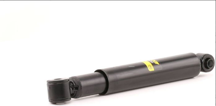 Black cylindrical hydraulic gas strut/damper lying on a white background, with a yellow label, used in automotive suspension.