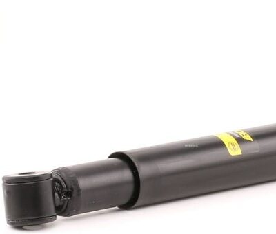 Black hydraulic shock absorber lying on a white background, showing its end mounts and yellow label.